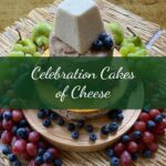 A tiered Bespoke Cake of Cheese topped with a wedge of cheese, surrounded by grapes, blueberries, and pears, with "Bespoke Cake of Cheese" across the center.